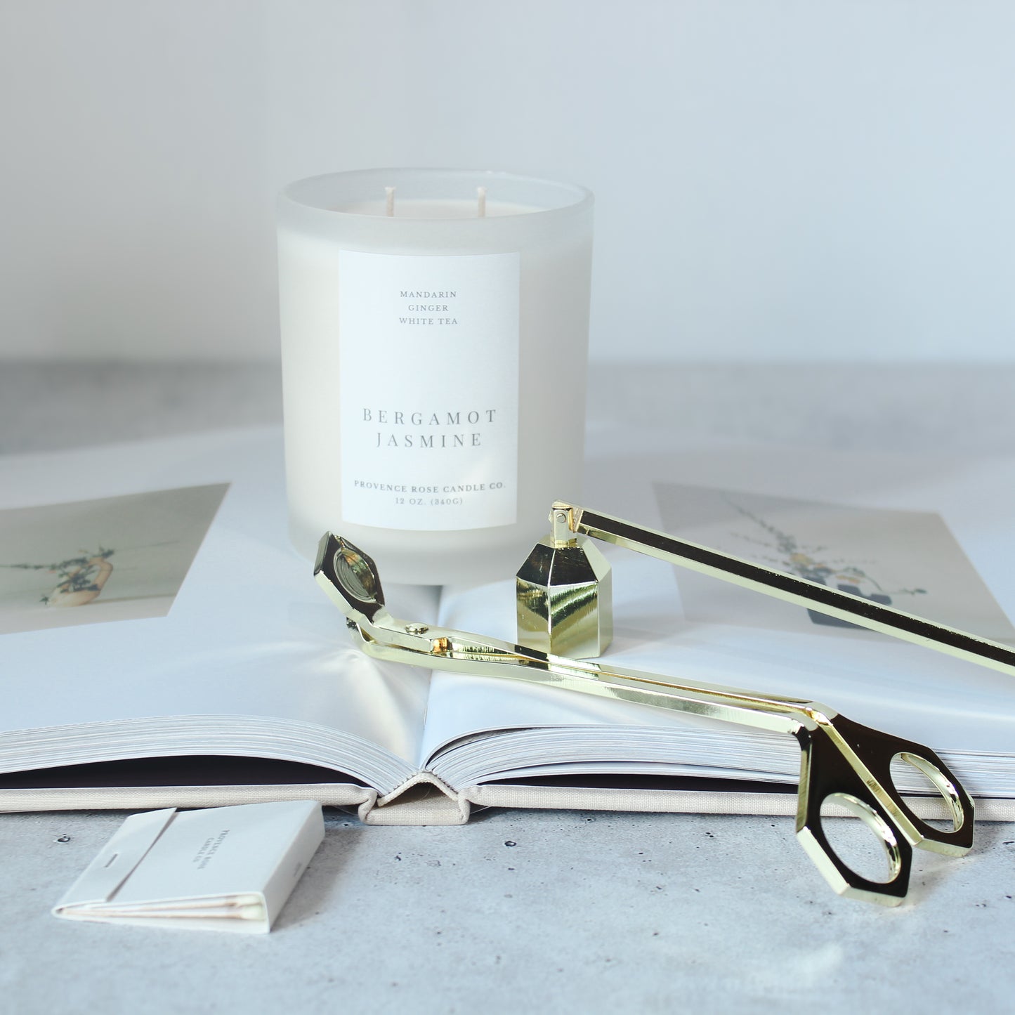 Candle with a decorative bottle and scissors on an open book